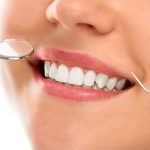 A woman is smiling while being at the dentist